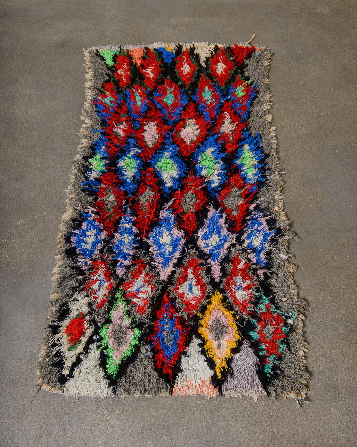 Colorful woven rug with geometric pattern on a gray background